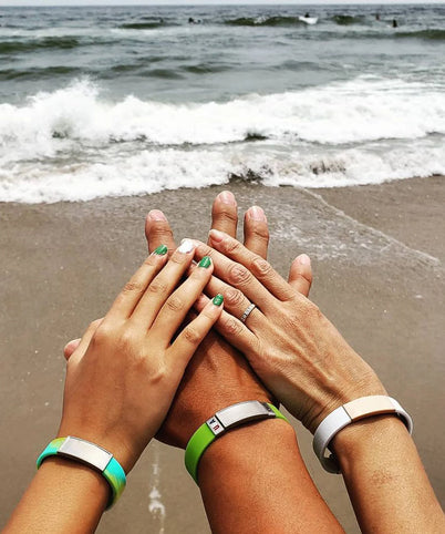 Image of three family members hands and wrists at beach, all wearing ROADiD Stretch ID.