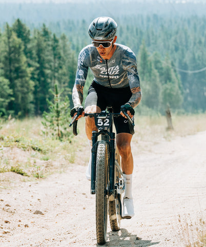 Cyclist riding a mountain bike on a dirt road with trees in the background